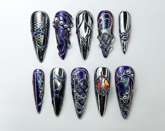 May include: Ten long, pointed, artificial nails with different iridescent and metallic finishes. Each nail has a different design featuring intricate patterns and details in shades of purple and silver.