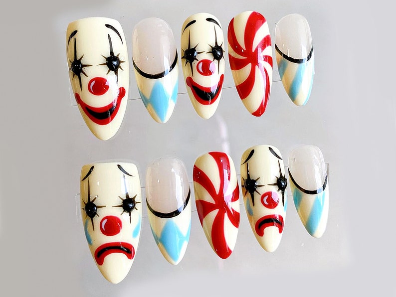 Peut inclure: Ensemble de dix faux ongles avec diff&eacute;rents motifs. Cinq ongles pr&eacute;sentent un visage de clown avec des l&egrave;vres rouges, des yeux noirs et un nez rouge. Trois ongles pr&eacute;sentent un motif en spirale bleu et blanc. Deux ongles pr&eacute;sentent un motif de canne en sucre rouge et blanc.
