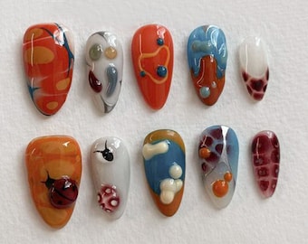 Puede incluir: Diez diseños de uñas diferentes con patrones abstractos, mariquitas y otros pequeños detalles. Los diseños están pintados en puntas de uñas en forma de almendra.