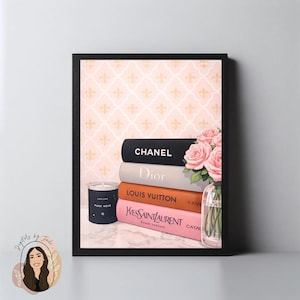 Può includere: Una stampa artistica incorniciata con una pila di libri di moda con i marchi Chanel, Dior, Louis Vuitton e Yves Saint Laurent. Sono inclusi anche un vaso di rose rosa e una candela nera con la scritta "Pure Noir".