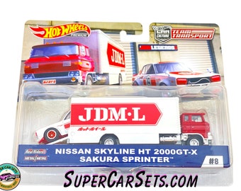 May include: A red and white toy truck with a white trailer. The trailer has the words "JDM-L" in red letters. The truck is carrying a white toy car with red accents. The car has the words "Nissan Skyline HT 2000GT-X Sakura Sprinter" on the side. The toy set is part of the Hot Wheels Team Transport Legends series.