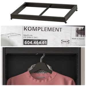 May include: Black metal shelf frame for a closet, with the IKEA KOMPLEMENT label and product number 604.464.61. The frame measures 19 5/8 inches by 13 3/4 inches.