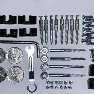 May include: An assortment of furniture hardware components, including screws, bolts, wooden dowels, and various metal fasteners. The hardware is arranged on a white surface, ready for assembly.