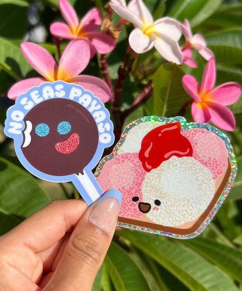 Peut inclure: Deux autocollants, l'un avec une sucette brune avec un visage bleu et rouge et le texte "No Seas Payaso" dans un cercle bleu, et l'autre avec un toast de dessin anim&eacute; rose et blanc avec une fraise rouge sur le dessus et un visage heureux.
