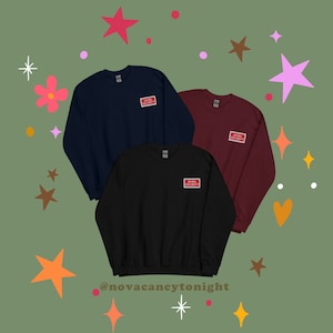 Könnte beinhalten: Drei Sweatshirts in Marineblau, Schwarz und Rotbraun mit einem roten Aufnäher auf der linken Brust, auf dem "Bean Security" steht.