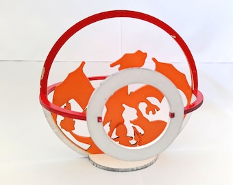 May include: A red and white wooden ornament with a cutout design of an orange dragon. The dragon is in a sphere shape with a red ring around it.