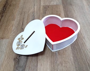 May include: White heart-shaped wooden box with a slot on the top and a floral design. The box is open and the inside is lined with red felt.