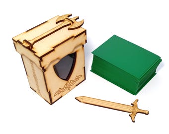 May include: A wooden card box with an axe design on the lid, a shield-shaped window, and Celtic knotwork. A wooden sword and a stack of green cards are also present. The box and sword are made of light-colored wood.