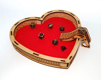 May include: A heart-shaped wooden dice tray with a red felt interior and a wooden slide. The tray is filled with various black and gold dice.