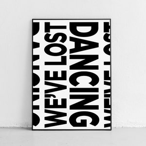 May include: A black and white framed poster with the words 'WE'VE LOST OUR DANCING SHOES' repeated in a vertical pattern.