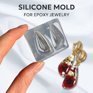 Puede incluir: Molde de silicona para hacer pendientes en forma de lágrima. El molde es transparente y tiene dos cavidades. La imagen también muestra un par de pendientes hechos con el molde, con un diseño floral.
