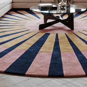Round hand-tufted rug, 9 ft, sunburst navy rays on pink and mustard wool blend, modern boho living room carpet.