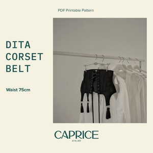 May include: Black corset belt with lace-up front and tassel details. The belt is hanging on a hanger with white shirts behind it. The text "DITA CORSET BELT" and "Waist 75cm" is visible on the left side of the image. The text "CAPRICE ATELIER" is visible at the bottom of the image.