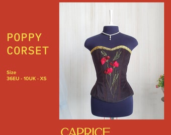 May include: A black velvet corset with red poppy embroidery and gold trim. The corset is on a mannequin and has a size tag that reads "36EU - 10UK - XS". The text "POPPY CORSET" and "CAPRICE ATELIER" are also visible in the image.
