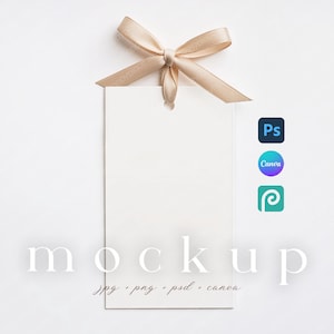 Può includere: Un'etichetta rettangolare bianca vuota con un fiocco di nastro beige in alto. La parola "mockup" è stampata in un colore chiaro sull'etichetta. Sotto la parola "mockup" ci sono le parole "jpg png psd canva". Le icone di Photoshop, Canva e Pinterest sono a destra.