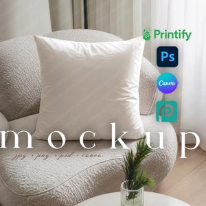 Op de afbeelding: Een wit vierkant kussen ligt op een gestructureerde, gebroken witte fauteuil. Het woord "mockup" wordt weergegeven in een groot, elegant lettertype. Hieronder is de tekst "jpg png psd canva" zichtbaar. De logo's van Printify, Photoshop, Canva en Placeit zijn ook aanwezig.