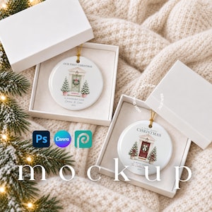 May include: Two white ceramic round ornaments in open gift boxes. Each ornament features a printed illustration of a front door with a wreath, two small pine trees, and text including Our First Christmas, A Very Merry Christmas, and dates.