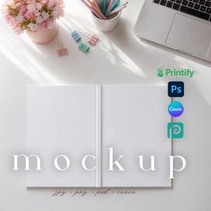 May include: A white book mockup with the word "mockup" in a serif font. The image includes a pink flower pot, colorful pencils, binder clips, and a laptop. The Printify, Photoshop, Canva, and Placeit logos are visible.