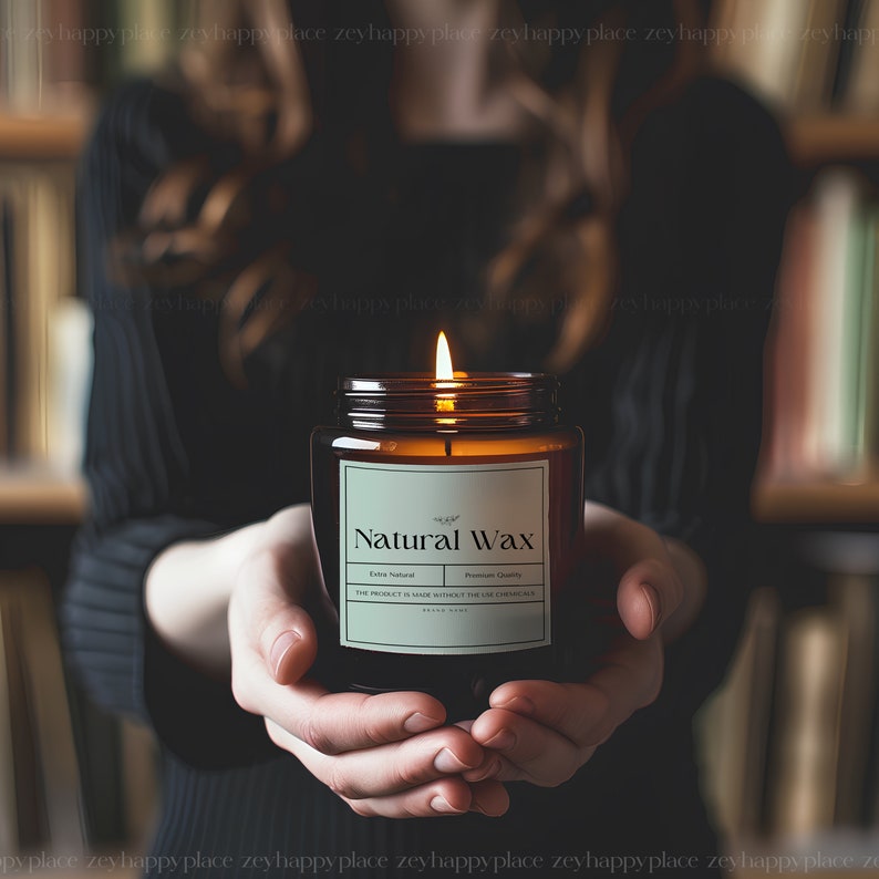Pu&ograve; includere: Una candela di vetro marrone con un'etichetta bianca su cui &egrave; scritto "Natural Wax" in un carattere verde. La candela &egrave; accesa e la fiamma &egrave; visibile. La candela &egrave; tenuta dalle mani di una persona.