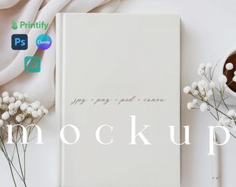 May include: White blank notebook mockup with a white pen, white flowers, and a white fabric in the background. The text "jpg - png - psd - canva mockup" is written in pink on the notebook.