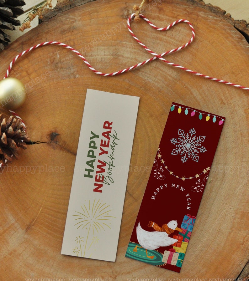 Puede incluir: Dos marcadores coloridos con saludos de A&ntilde;o Nuevo. El primer marcador es beige con texto dorado que dice "Happy New Year" y un dise&ntilde;o de fuegos artificiales dorados. El segundo marcador es rojo con un copo de nieve blanco, un pato blanco que lleva regalos y el texto "Happy New Year".