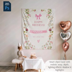 May include: A white birthday banner with floral and pink bow accents. The banner reads "HAPPY BIRTHDAY OLIVIA WE LOVE YOU". Three heart-shaped balloons in rose gold and silver are to the right. A small cake with candles sits on a table.
