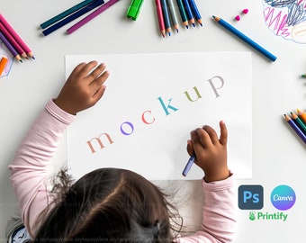 Op de afbeelding: De hand van een kind schrijft het woord "mockup" op een wit vel papier met kleurpotloden eromheen. Het kind draagt een roze longsleeve shirt. De afbeelding bevat ook logo's voor Photoshop, Canva en Printify.