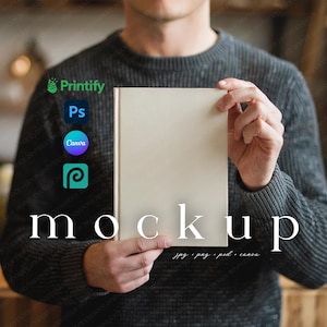 May include: A person holding a blank, off-white book mockup. The word "mockup" is displayed in white, along with the file types: jpg, png, psd, and canva. The Printify, Ps, Canva, and Placeit logos are also visible.