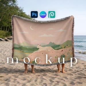 Peut inclure: Une couverture tissée pêche avec un motif de paysage représentant un léopard, des montagnes et un croissant de lune. La couverture a une bordure à franges et le mot "mockup" en texte blanc.
