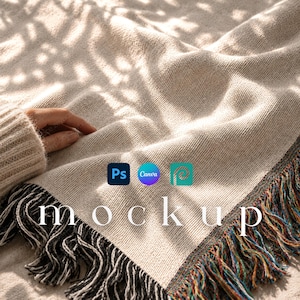 Puede incluir: Una manta tejida de color beige con una superficie de punto texturizado y bordes con flecos decorativos en hilos negros, blancos y multicolores. La manta muestra la palabra mockup en texto blanco, acompañada de iconos azules, morados y turquesas.