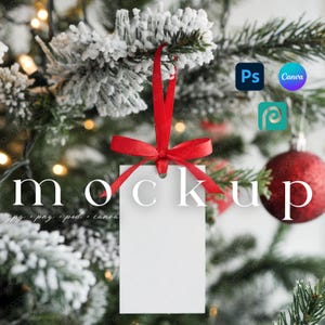 May include: A white rectangular tag with a red ribbon and bow, hanging from a snow-covered Christmas tree branch. The word "mockup" is printed on the tag. The background includes Christmas ornaments and lights.