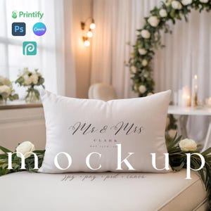 Könnte beinhalten: Ein weißes rechteckiges Kissen mit den Worten "Mr & Mrs Clark" und dem Datum "May 11th, 24" in eleganter Schrift. Das Wort "Mockup" wird darunter in einer serifenlosen Schriftart angezeigt. Das Kissen liegt auf einer weißen Oberfläche mit Grün.