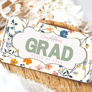 May include: A white chocolate bar wrapper featuring a floral design in shades of blue, yellow, and pink. The text "Congratulations Grad Class of 2025" is printed on the wrapper.