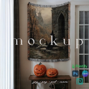 May include: A tapestry featuring a gothic scene with a witch and a black cat, displayed on a wall. Two carved orange pumpkins with smiling faces sit on a wooden table. The word "mockup" is printed on the tapestry.