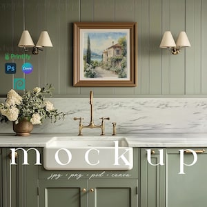 May include: A white farmhouse style kitchen sink with a gold faucet and a marble countertop. The backsplash is green wood paneling with a framed watercolor painting of a house and a lake. The cabinets are green with gold hardware.