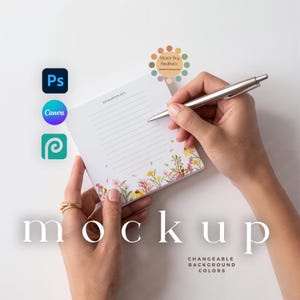 May include: A mockup image featuring a notepad with floral accents, held by hands with a pen poised to write. The word "mockup" is displayed prominently. Icons for Photoshop, Canva, and Procreate are visible.