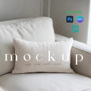 May include: A cream-colored rectangular pillow with the word "mockup" printed on it, resting on a white sofa. The pillow has a textured surface. The text "jpg, png, psd, canva" is printed below the word "mockup".