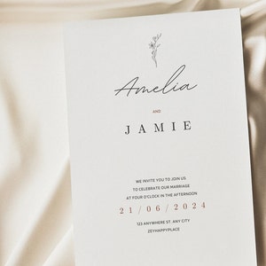 May include: A minimalist wedding invitation with a simple floral illustration. The invitation reads "Amelia and Jamie" with the wedding date "21/06/2024" and the address "123 Anywhere St. Any City, Zeyhappyplace".