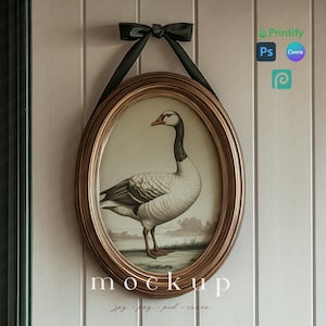 May include: An oval framed print featuring a goose illustration, with a gold-colored frame and a dark green ribbon for hanging. The print has a vintage aesthetic, with the word "mockup" at the bottom.