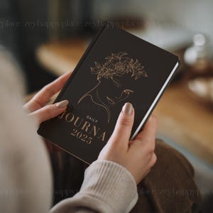 May include: A black daily journal with a gold floral design and the text "DAILY JOURNAL 2025" on the cover.