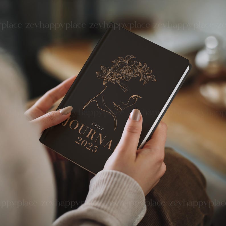 May include: A black daily journal with a gold floral design and the text "DAILY JOURNAL 2025" on the cover.