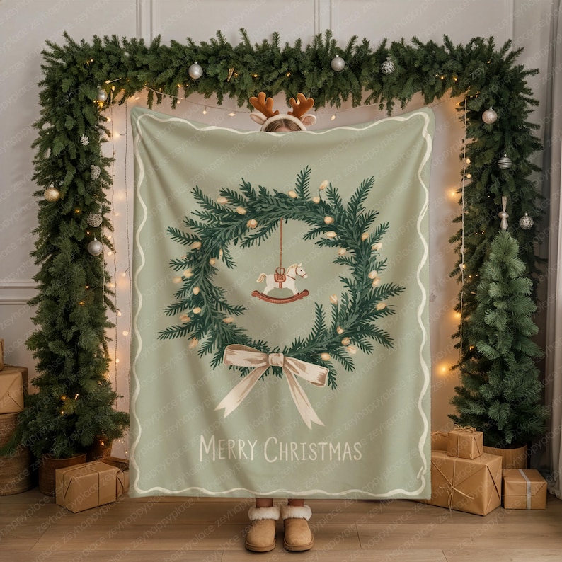May include: A sage green Christmas blanket featuring a wreath design with a rocking horse, bow, and the words "Merry Christmas." The blanket has a white border and is surrounded by Christmas decorations.