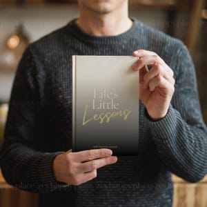 Puede incluir: Un diario negro y blanco con un degradado dorado y el texto "Life's Little Lessons" y "Self-Discovery Journal".