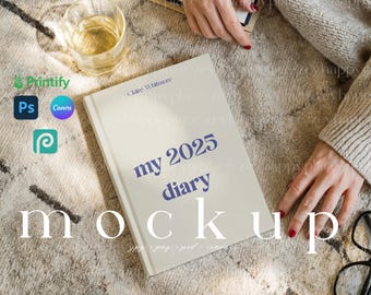 May include: A white diary with the text "my 2025 diary" in blue lettering. The diary is lying on a beige rug with a glass of water and a pair of glasses.