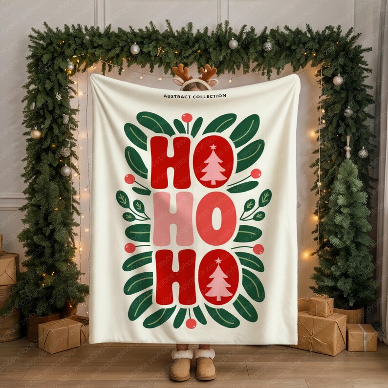 May include: A cream-colored blanket with the words "HO HO HO" in red and pink, with a Christmas tree design. The blanket is surrounded by green leaves and red berries, with the text "ABSTRACT COLLECTION" at the top.