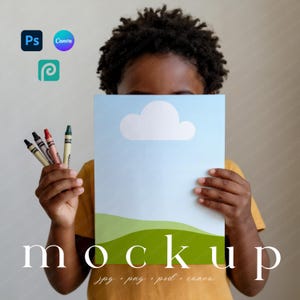 May include: A child holding a blue and white mockup with a cloud and green hills design. The word "mockup" is at the bottom, with "jpg, png, psd, canva" below it. Crayons are held in the other hand. Photoshop, Canva, and Procreate logos are in the top left.