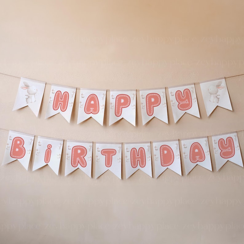 May include: A white banner with pink letters spelling "Happy Birthday" with a bunny rabbit on each end.