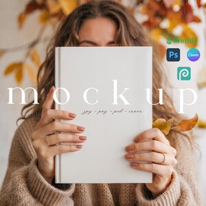 May include: A white book mockup held in front of a person. The word "mockup" is printed on the book in a large, elegant font. The book is surrounded by fall foliage and the text "jpg, png, psd, canva".