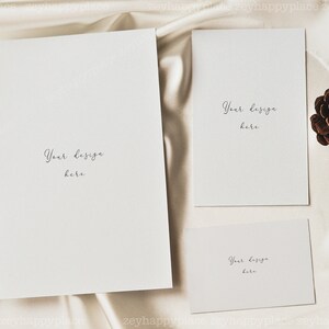 May include: Three blank cards with the text "Your design here" on a white satin background. A brown pine cone is on the right side of the image.