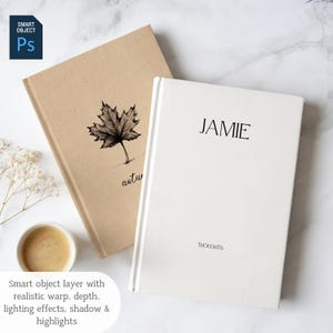 May include: Two hardcover journals. One is beige with a black maple leaf illustration and the word "autumn" in script. The other is white with the name "JAMIE" and the word "THOUGHTS" in black text.